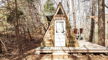 Una baita di legno con tetto a punta, una porta bianca e un pontile in legno.