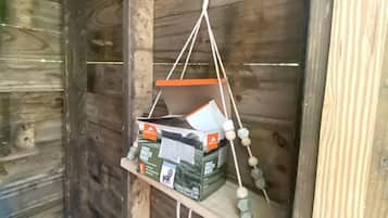 A wooden wall with a hanging shelf containing a trash bag and a small box.
