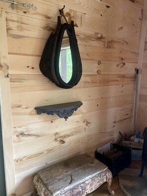 Un interior de madera con un banco, una estantería y un bolso colgado.