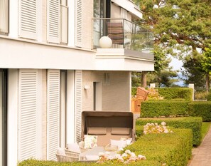 Een modern huis met een balkon, een tuin met hagen en bloemen, en een pad.