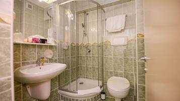 Un baño con ducha de mampara, lavamanos e inodoro.