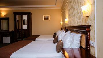 A hotel room with two beds, a wooden headboard, a desk, and a mirror.