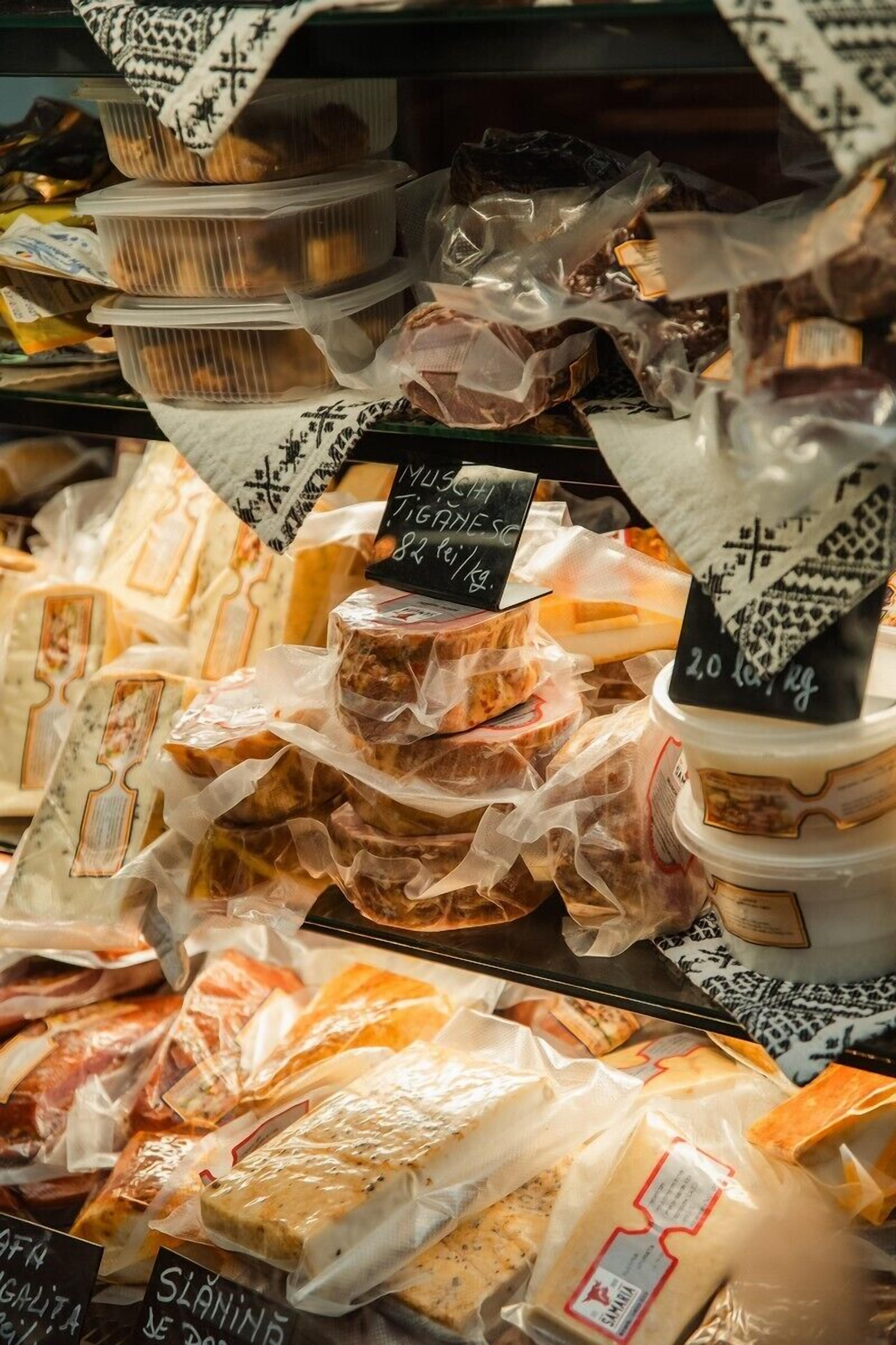 Variedad de quesos y embutidos envasados exhibidos en una tienda.