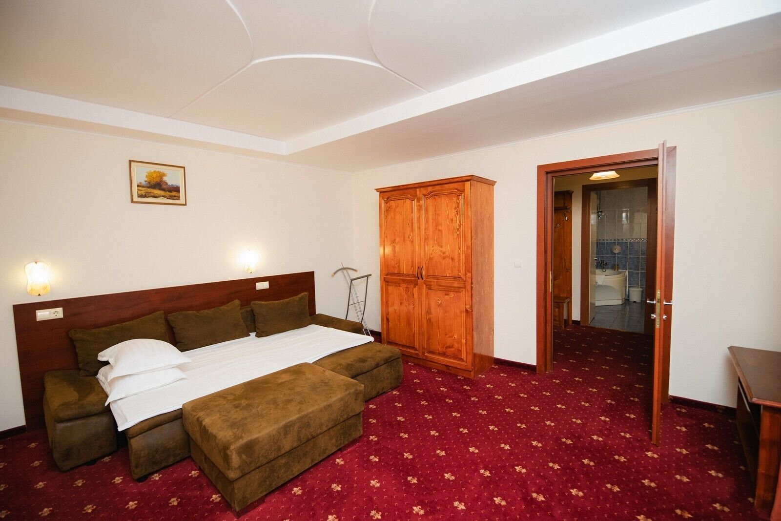 Ein Schlafzimmer mit Bett, Kleiderschrank und einem durchgegangenen Tür angedeuteten Badezimmer.