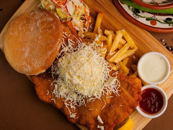 A meal consisting of a breaded fish fillet, fries, coleslaw, and two dipping sauces. - Fântânița Haiducului (Şelimbăr)