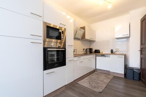 Eine moderne Küche mit weißen Schränken, Edelstahlgeräten und Holzboden.