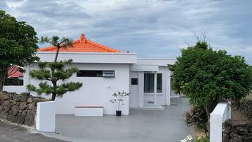 A modern house with a white exterior, orange roof, and a small front porch.