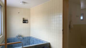 Une salle de bain avec une baignoire, une douche et des toilettes. On y trouve des articles de toilette accrochés au mur et un porte-serviettes.
