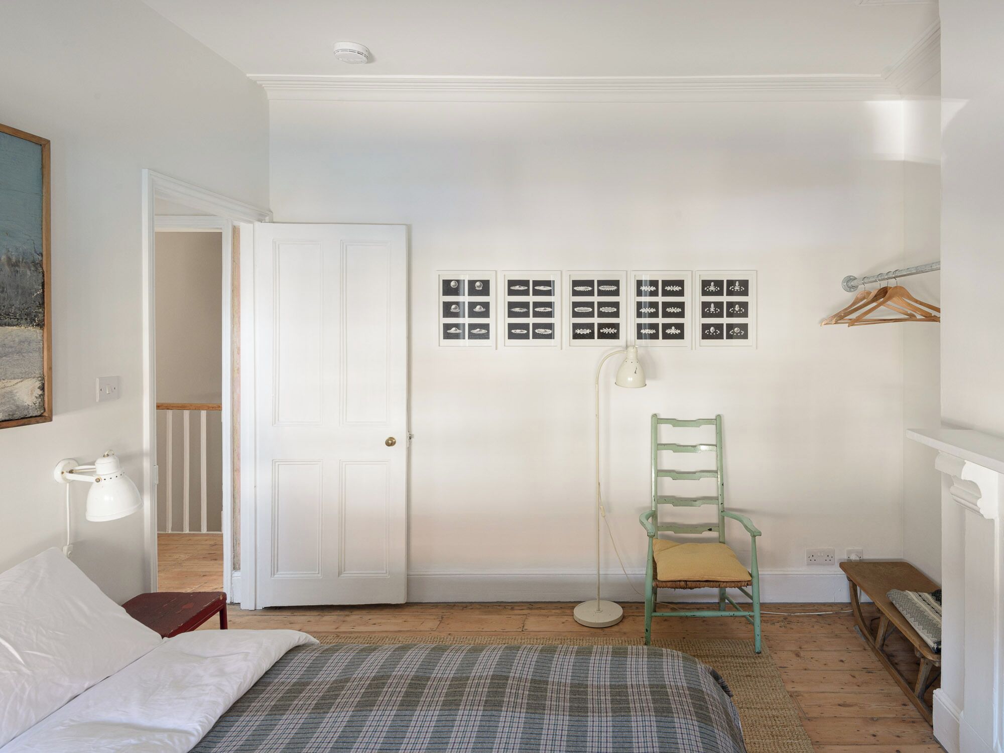 Ein Schlafzimmer mit Bett, Stuhl, Stehlampe und einer Tür.
