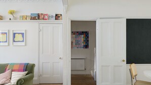 A room with a green sofa, a small wooden stool, a chair, and a blackboard wall. - Beautiful 3 Bedroom Home in Bristol (Bristol)