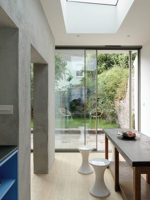 A modern interior with a skylight, a dining area with a table and chairs, and a view of a garden through large glass doors. - Beautiful 3 Bedroom Home in Bristol (Bristol)