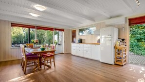 A spacious kitchen with wooden cabinets, a dining area with a table and chairs, and a view of greenery outside. - "Leani" - 150m from the sea by Interhome (Ørsted)