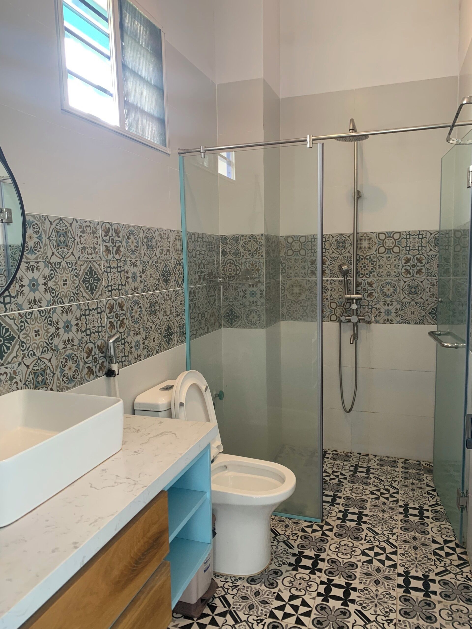A bathroom with a glass-enclosed shower, a white sink, and a toilet.