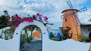 Un moulin à vent, une arche blanche et un bâtiment orné d’une fresque murale.