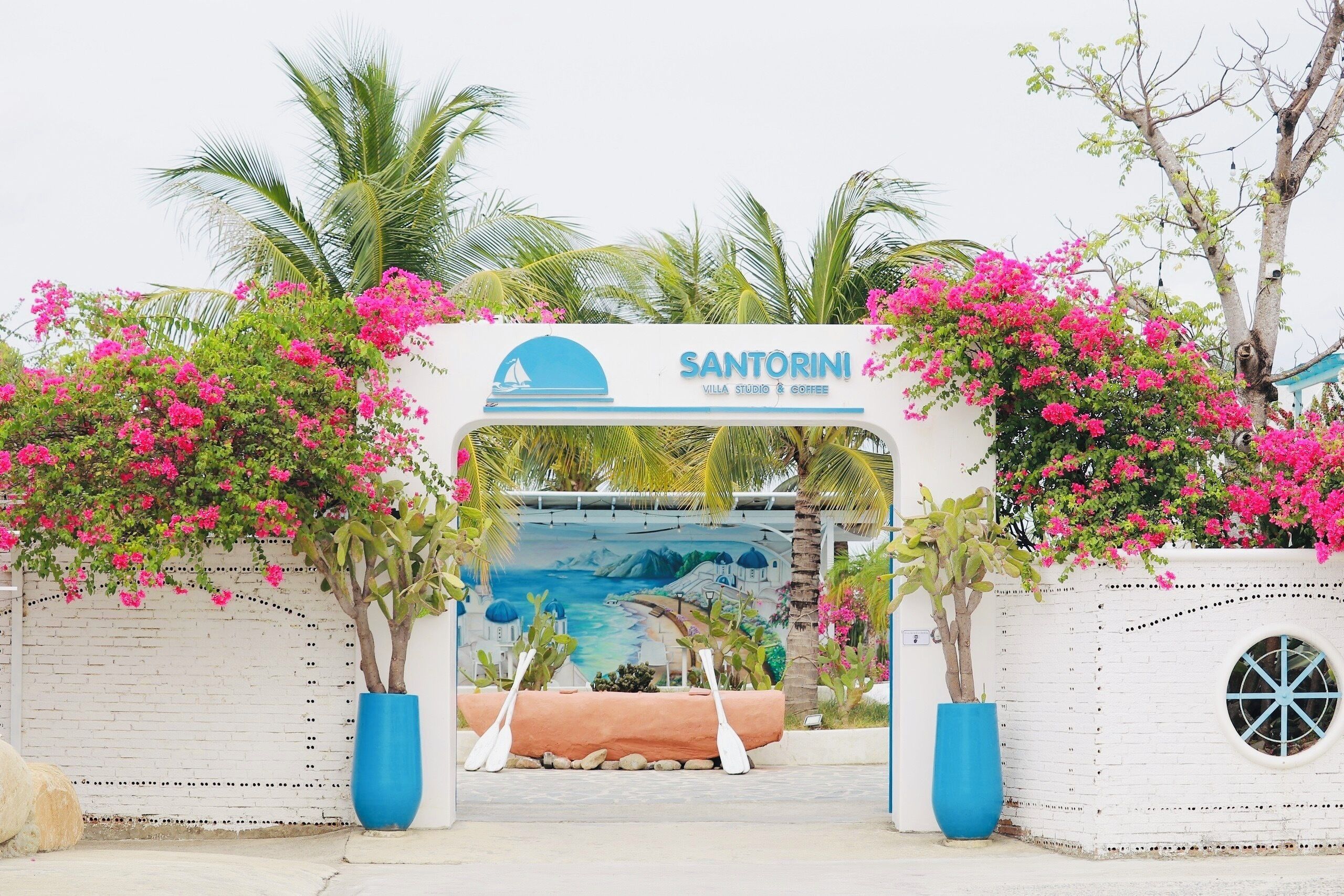 A hotel entrance with a sign reading "SANTORINI VILLA STUDIO & COFFEE".