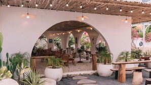 Un espace extérieur aménagé avec des arches, des plantes en pot et des allées pavées.