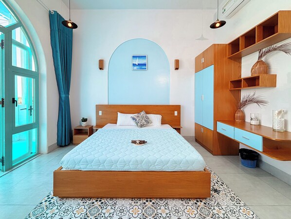 A modern bedroom with a large bed, wooden headboard, and a built-in wardrobe. - santorinivilla.vn (Bac Cam Ranh)