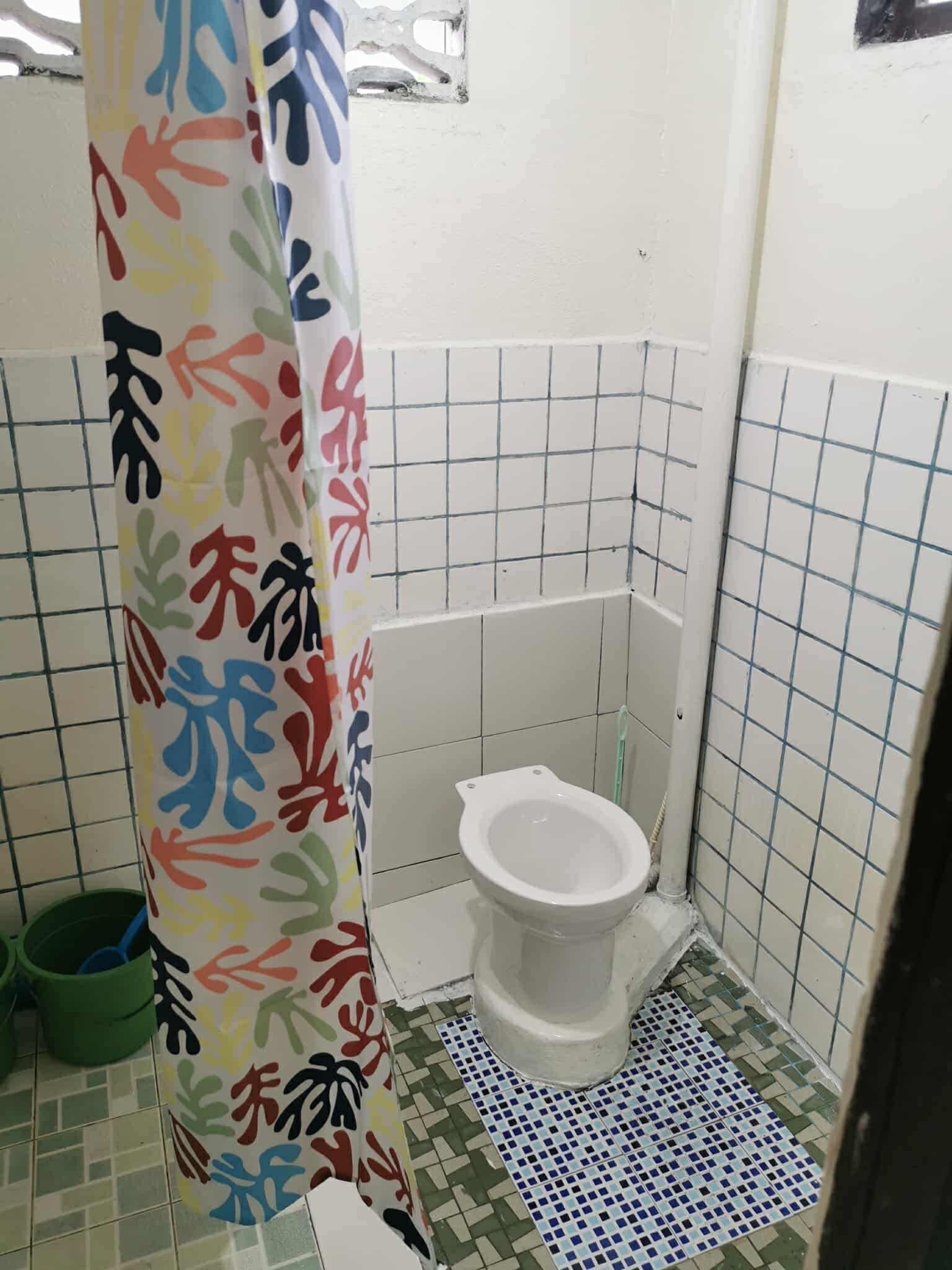 A small bathroom with a toilet, a shower curtain with colorful patterns, and tiled walls and floor.
