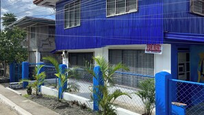 A blue building with a 'For Rent' sign, a gated entrance, and a small garden with palm trees. - Charming 1-bedroom apartment house in Pinamalayan,Oriental Mindoro (Mimaropa)