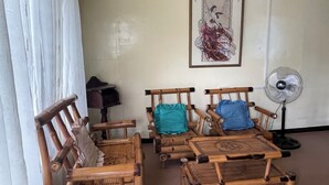 A room with a ceiling fan, a painting on the wall, and two wooden chairs with cushions. - Charming 1-bedroom apartment house in Pinamalayan,Oriental Mindoro (Mimaropa)