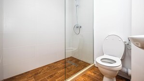 A bathroom with a glass-enclosed shower, a toilet, and wooden flooring. - Stefan Building Mamaia Nord (Mamaia-Sat)