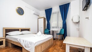 A hotel room with a wooden bed, a small table, two chairs, a clock, and a window with blue curtains. - Stefan Building Mamaia Nord (Mamaia-Sat)