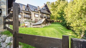 Een rustieke lodge met een gevel van natuursteen, houten balkons en een gazon.