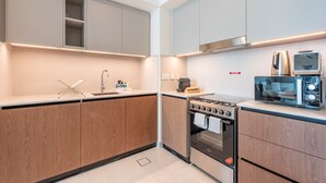 Una cucina moderna con mobili in legno, forno integrato, microonde e macchina da caffè.