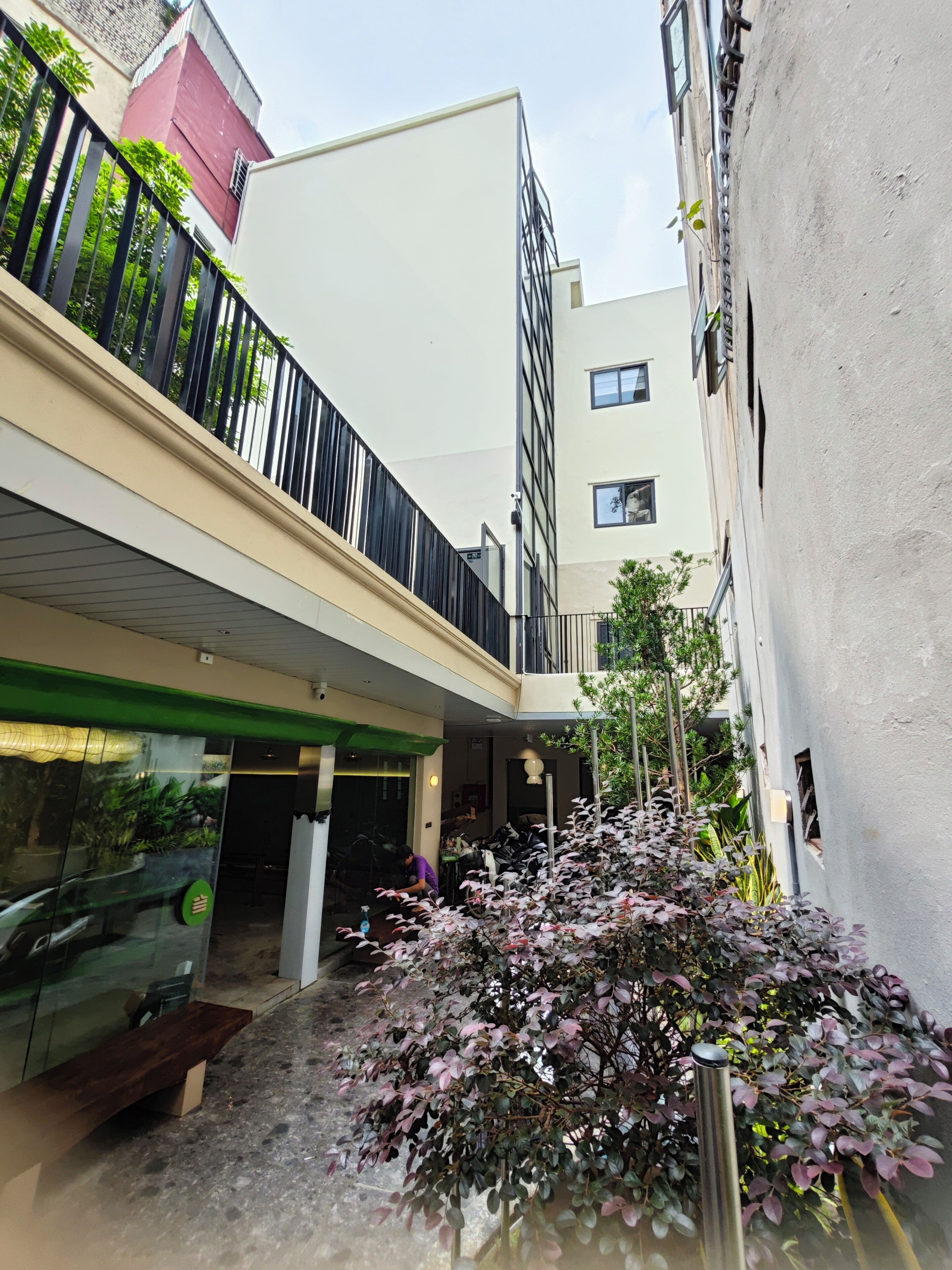 Un edifici modern amb teulada plana, un balcó amb baranes negres i un told verd sobre l'entrada.