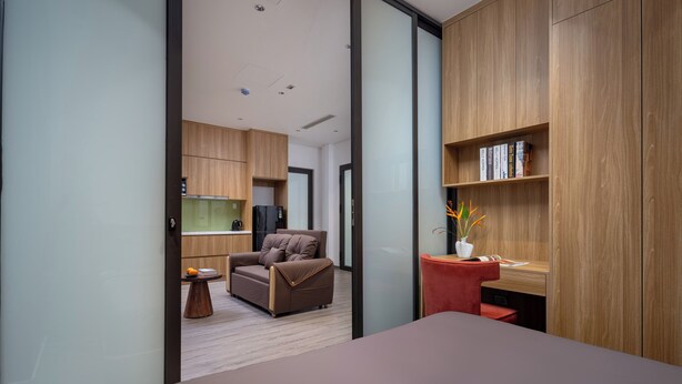 A modern bedroom with a bed, a desk, a chair, and a kitchenette. - Minerva Aparthotel Hanoi (Hanoi)