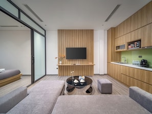 Un espacio de sala moderno con un sofá, un reposapiés y una mesa de centro de vidrio.