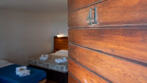 A wooden wall with the number '41' indicating room number, a bed with a blue bedspread, and a bedside table with a lamp. - Tenuta dell'Argento - Room 1 by Rentbeat  (Civitavecchia)