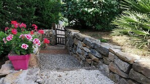 Une entrée de jardin agrémentée d’un mur en pierre, d’un chemin de gravier et d’une porte en bois.