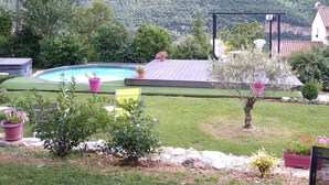 Un jardin avec une piscine, une pergola en bois et une vue sur un paysage montagneux.