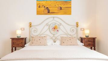 A bedroom with a bed, two nightstands, a wall-mounted painting, and a decorative headboard.