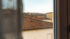 Une vue sur une ville, prise à travers une fenêtre, avec des toits et des bâtiments aux couleurs ocre.