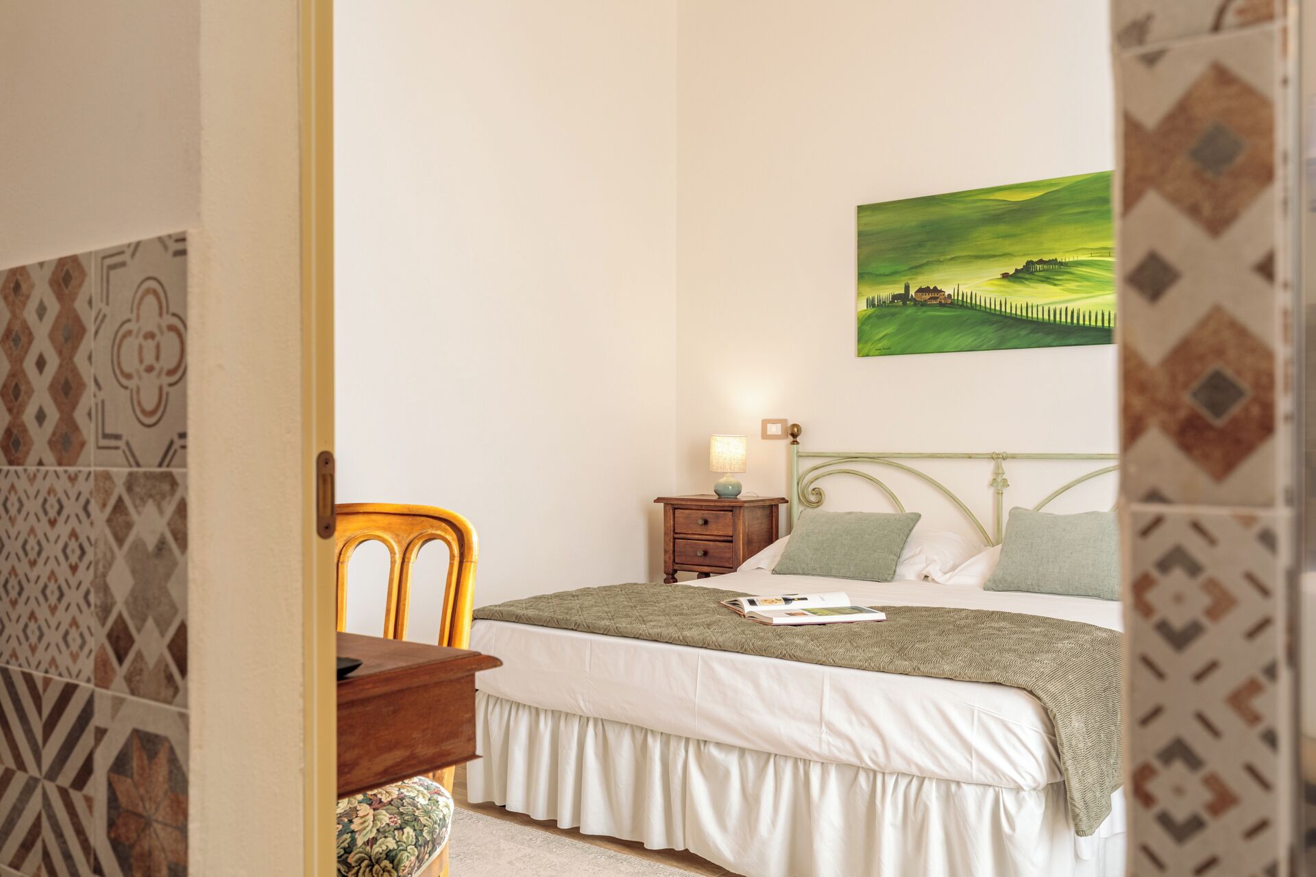 Une chambre à coucher avec un lit, une table de chevet, une chaise et un tableau accroché au mur.