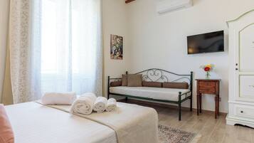 A bedroom with a bed, a sofa, a TV, a small table, and a wardrobe.