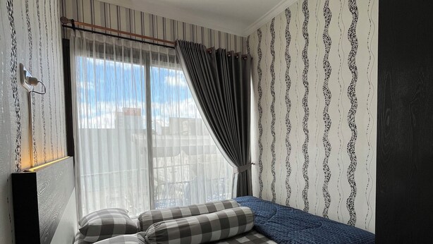 A bedroom with a bed, curtains, a window, and patterned wallpaper. - Arrayyan Executive Village Complex Batu (Batu)