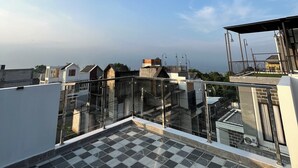 A rooftop terrace with a checkered floor, a glass railing, and a view of neighboring buildings. - Arrayyan Executive Village Complex Batu (Batu)