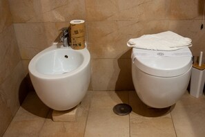 Een douche, een bidet, handdoeken, shampoo