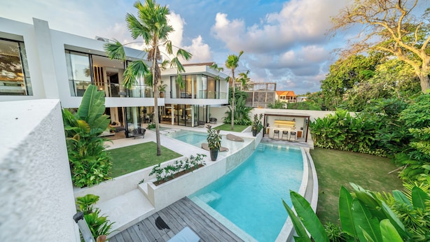 A modern house with a swimming pool, surrounded by lush greenery and palm trees. - Villa Fortuna by RPM (Kerobokan)