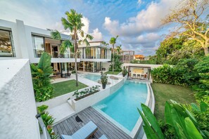 Uma casa moderna com piscina, rodeada por vegetação exuberante e palmeiras.