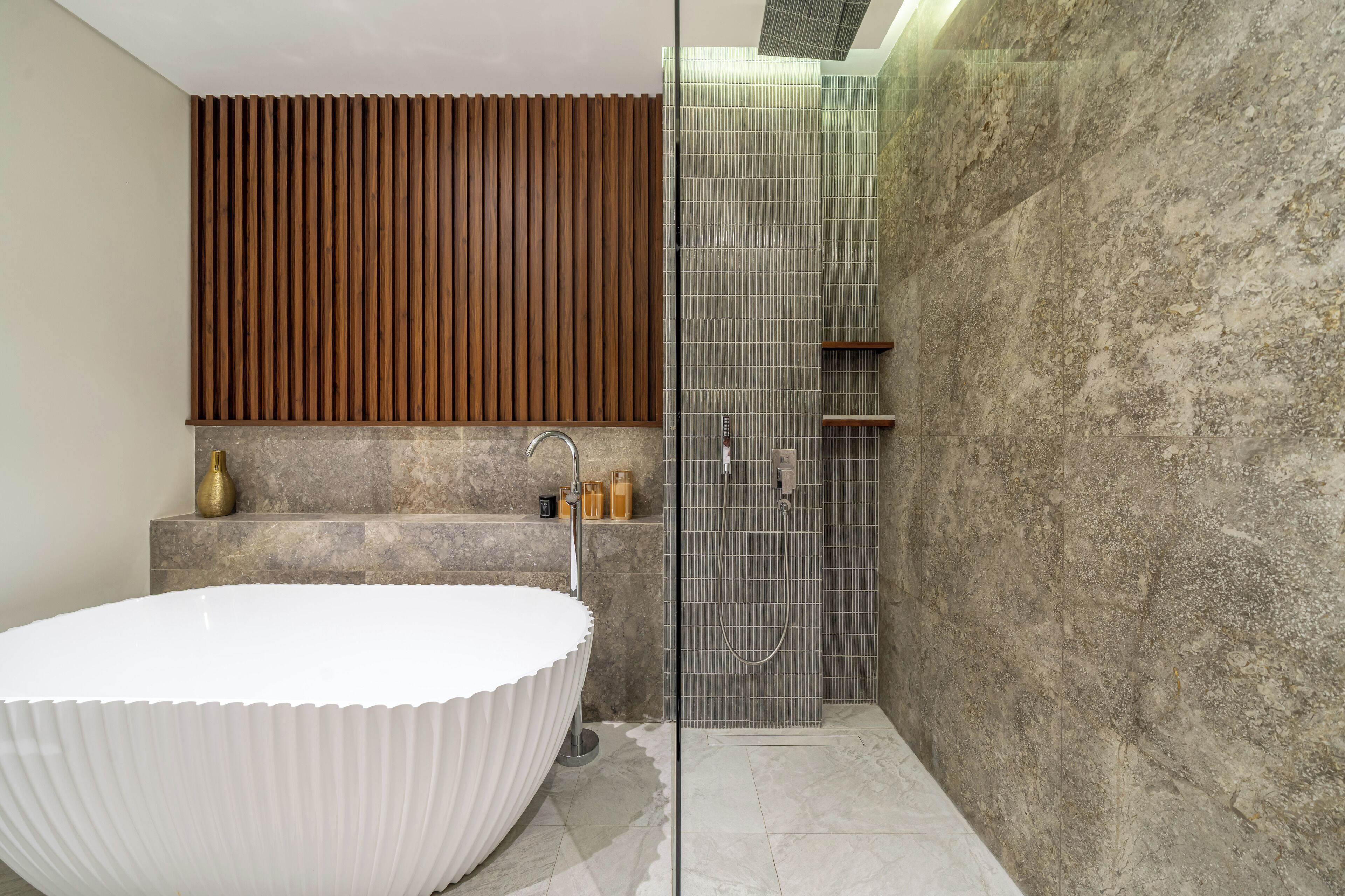 Un baño moderno con una bañera independiente, ducha con cerramiento de vidrio y pared revestida de madera.