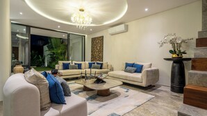 A modern living room with a sectional sofa, a coffee table, and a chandelier. - Villa Fortuna by RPM (Kerobokan)