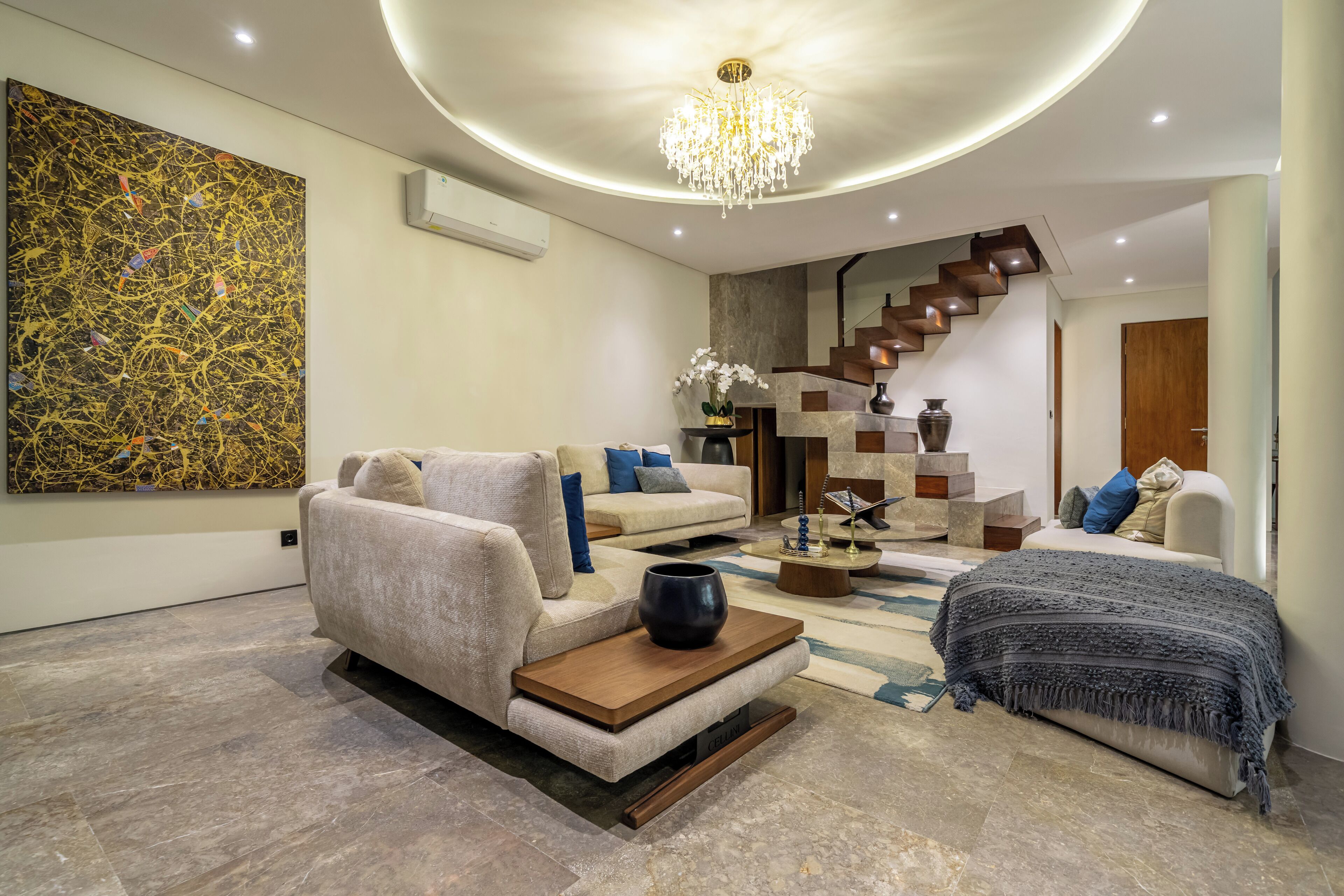A modern living room with a beige sofa, a coffee table, and a staircase leading to another level.