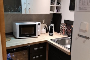 A compact kitchen with a microwave, toaster, and sink.