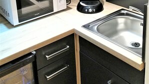 Une cuisine équipée d’un four à micro-ondes, d’un grille-pain et d’un évier en acier inoxydable.