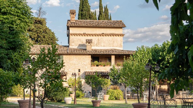 Un edificio de estilo arquitectónico tradicional, rodeado por un jardín con plantas en macetas y un camino de grava.