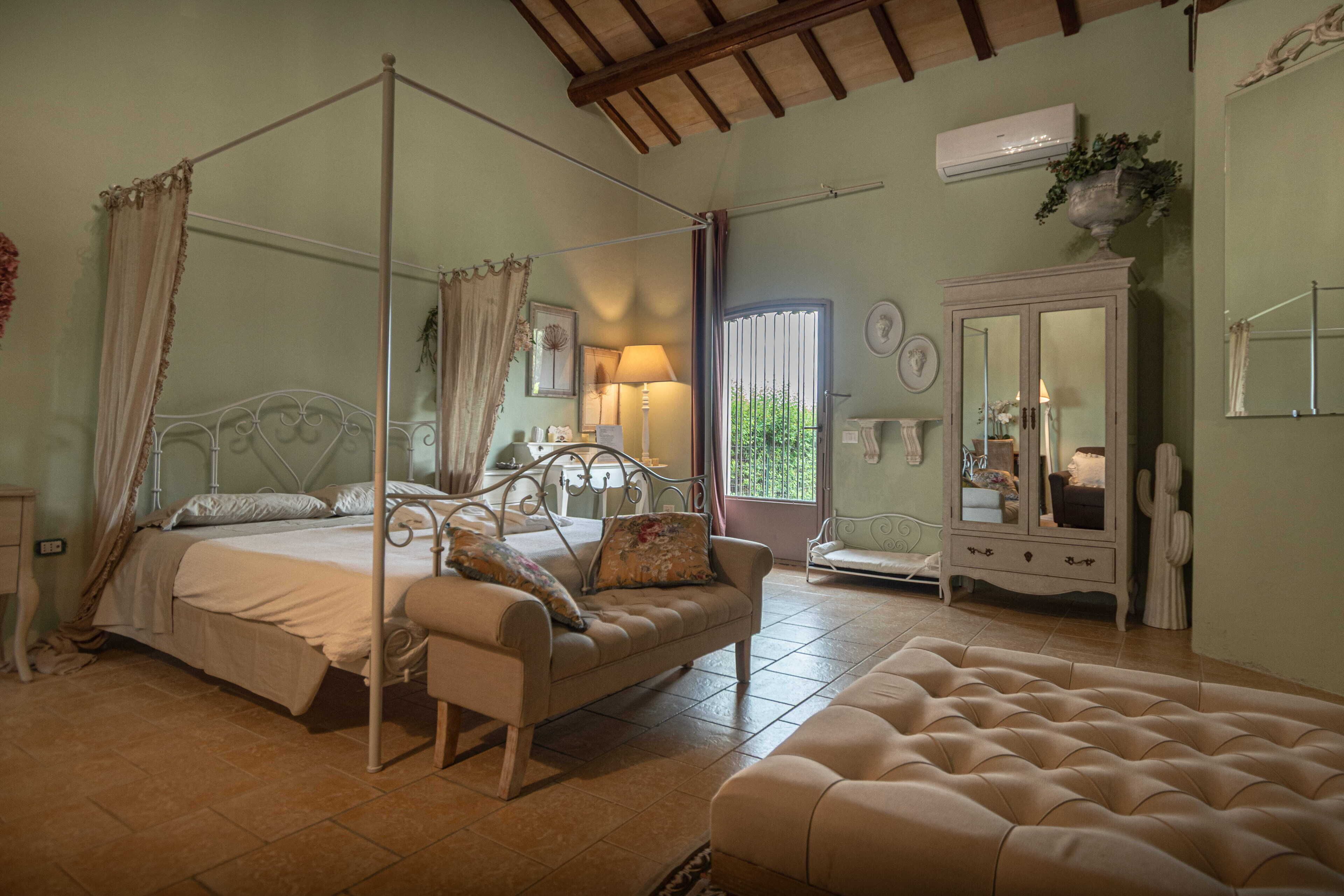 A bedroom with a four-poster bed, a daybed, a cabinet, and a mirror.